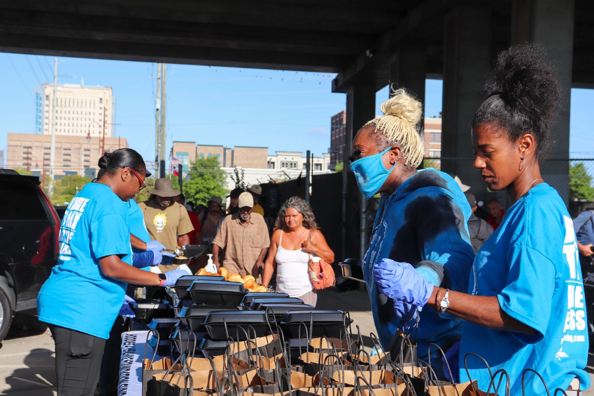 A group of people wearing blue shirts are standing around a table.