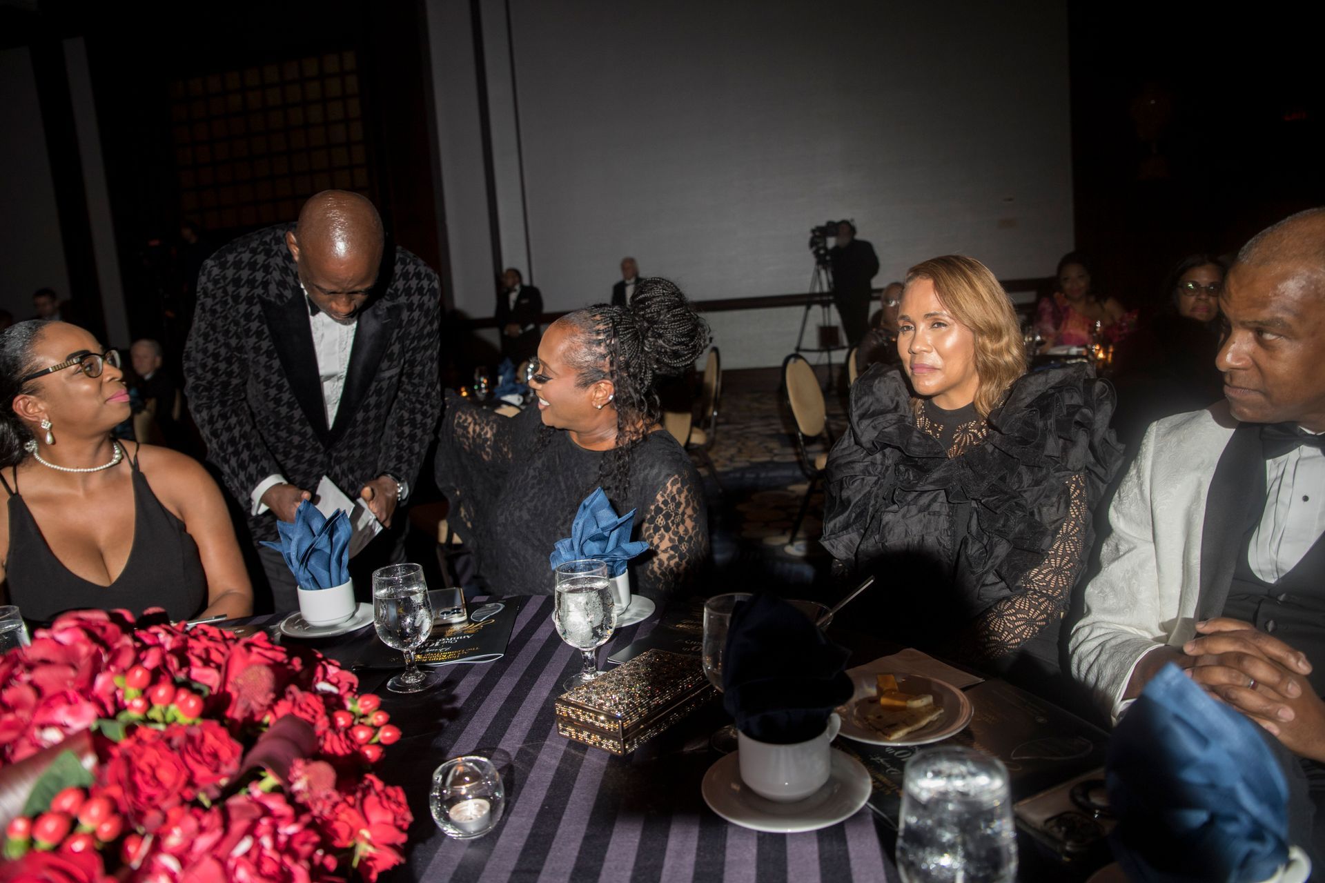 A group of people are sitting at a table in a dark room.