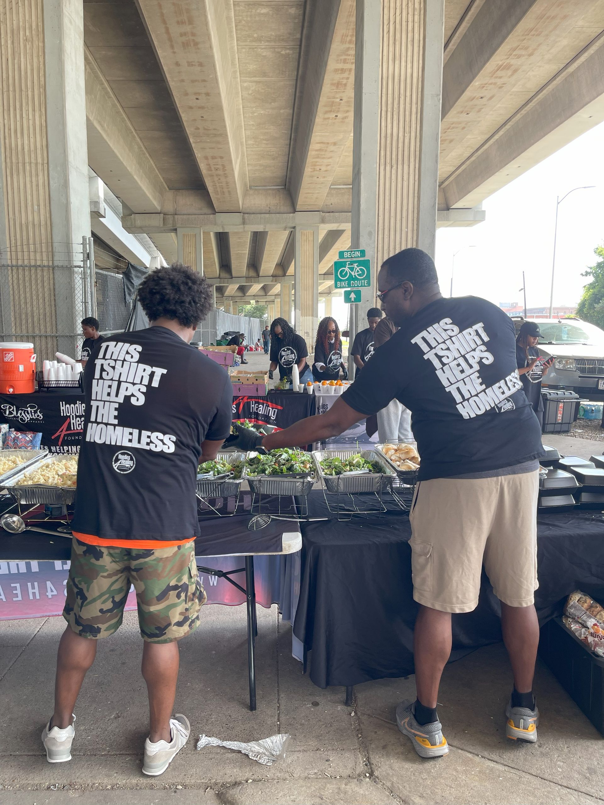 Two men are standing in front of a table with food.