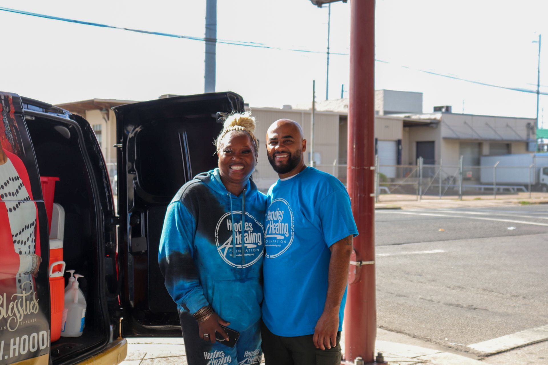 A man and a woman are posing for a picture in front of a van.