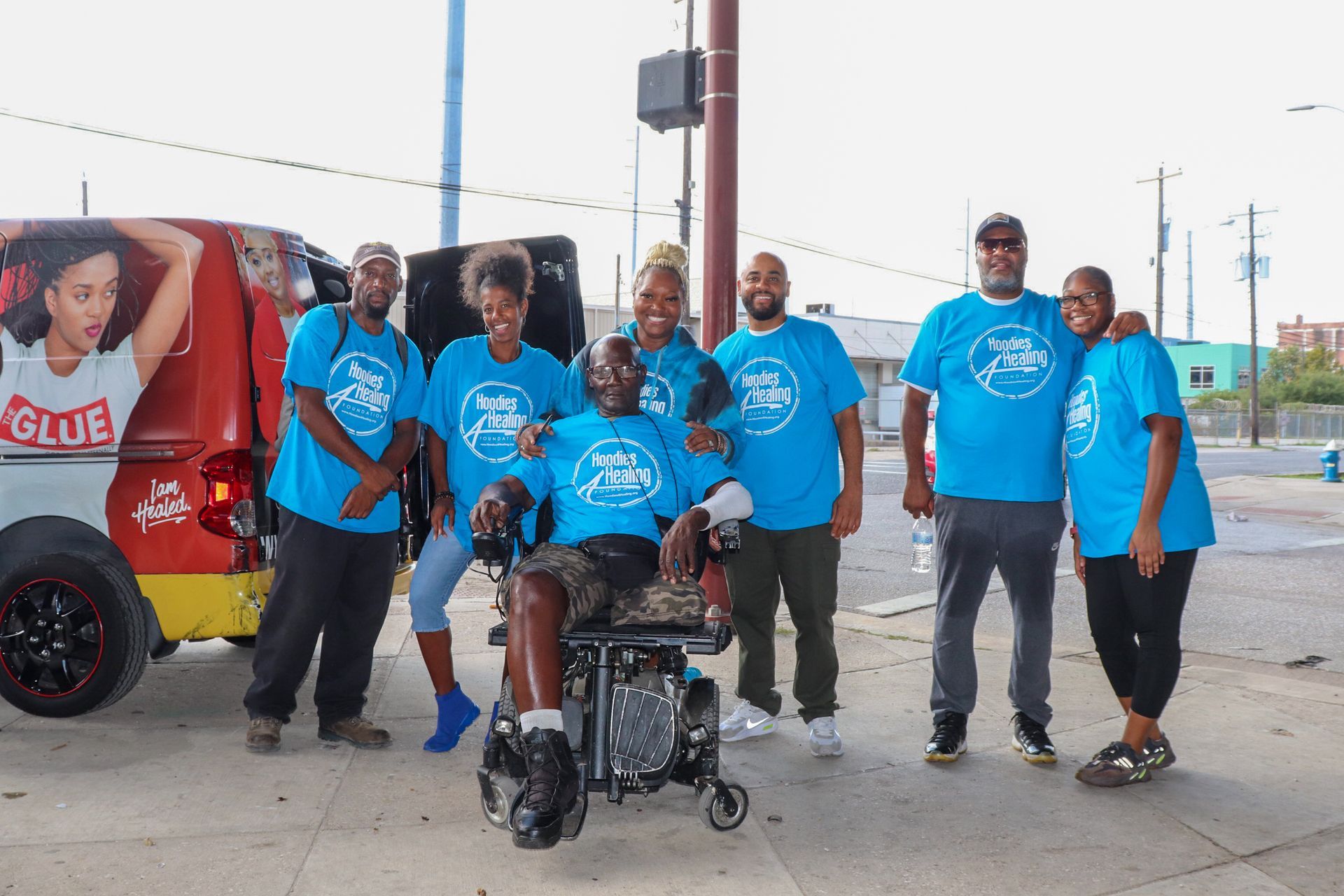 A group of people are posing for a picture with a man in a wheelchair.