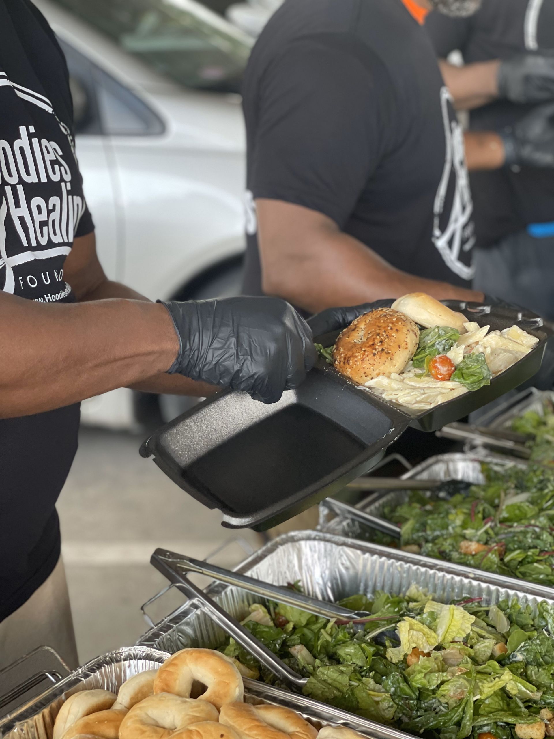 A man wearing black gloves is holding a tray of food.