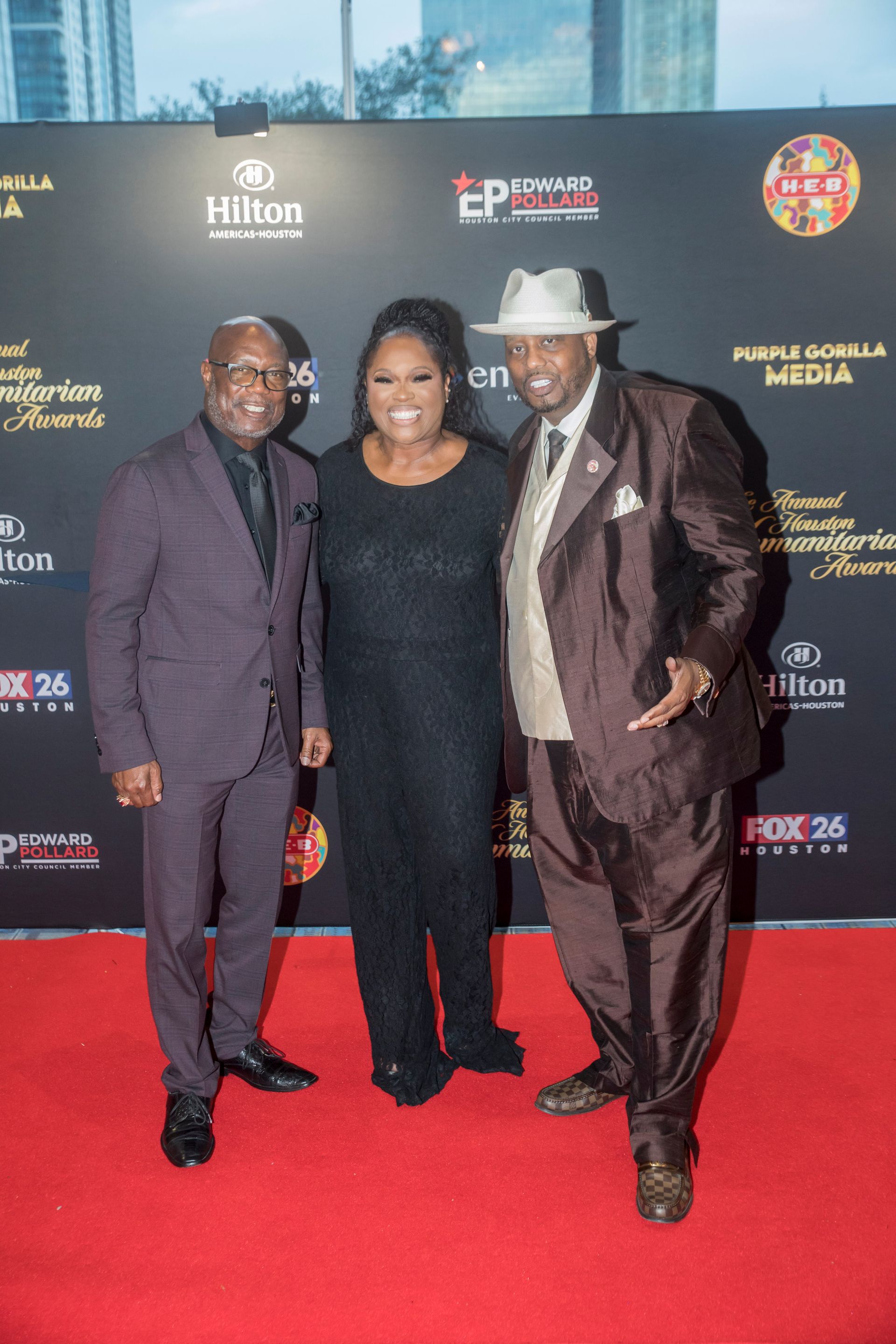 Three people are standing next to each other on a red carpet.