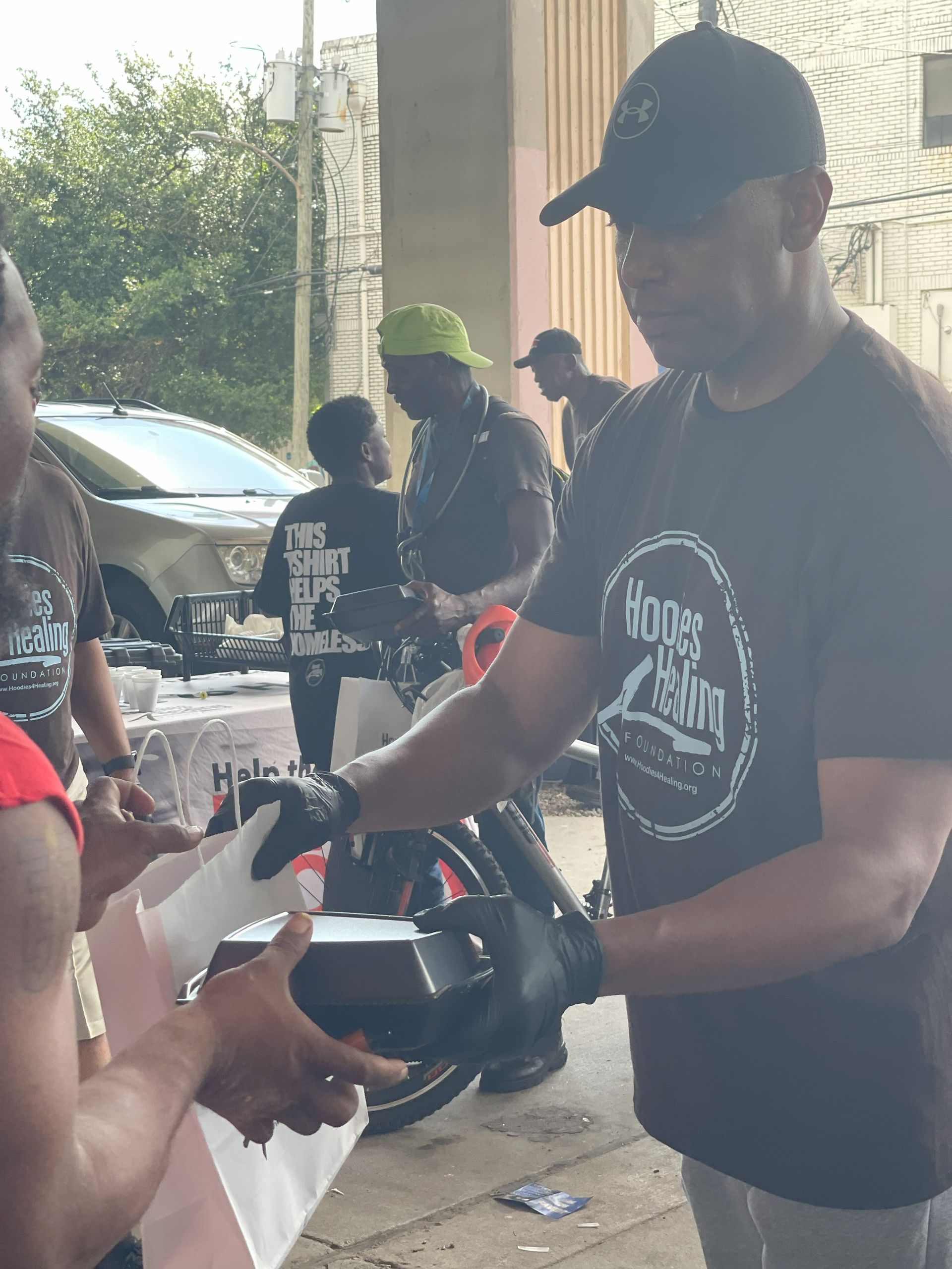 A man in a black t-shirt is giving a woman a steering wheel.