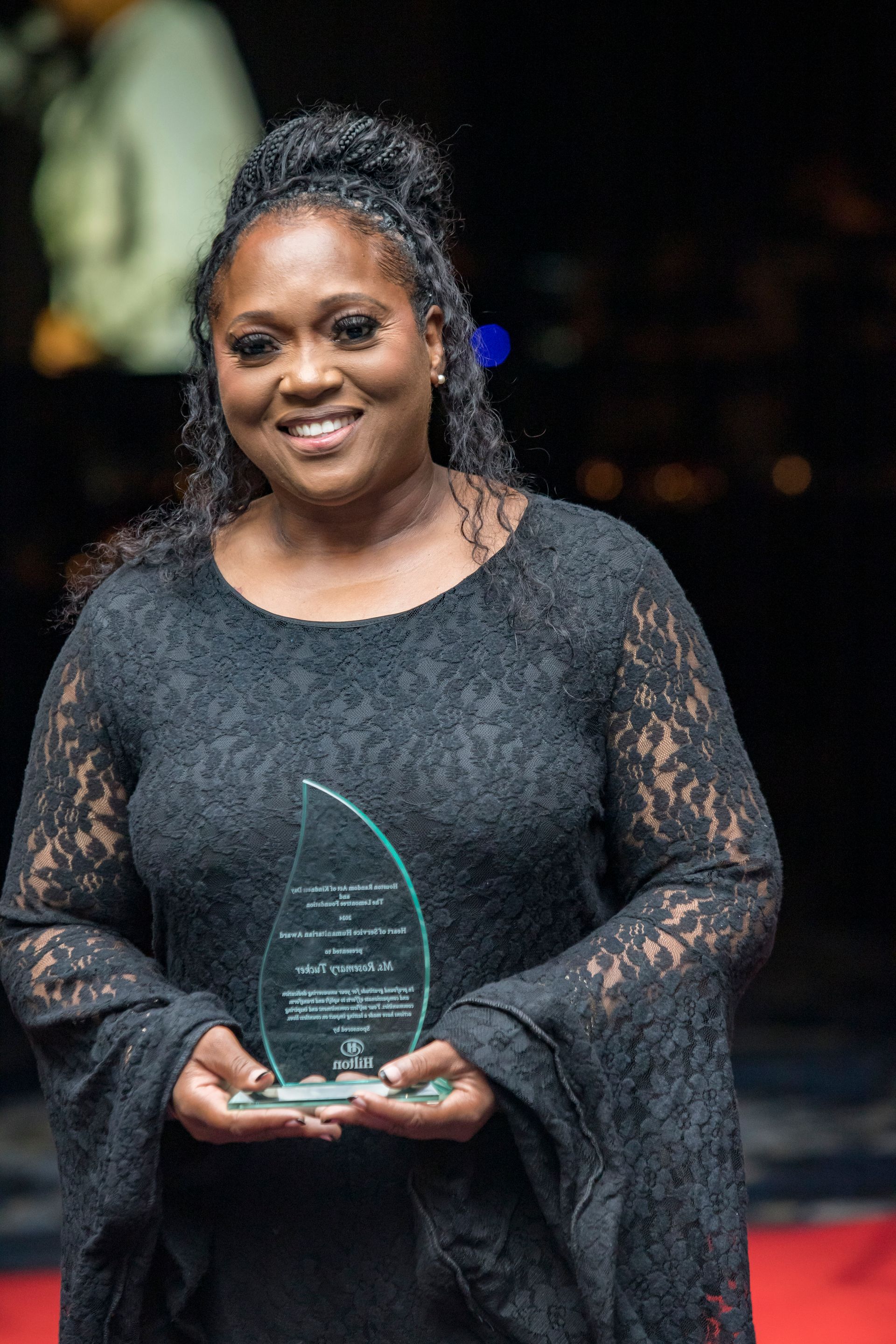 A woman in a black dress is holding a trophy.
