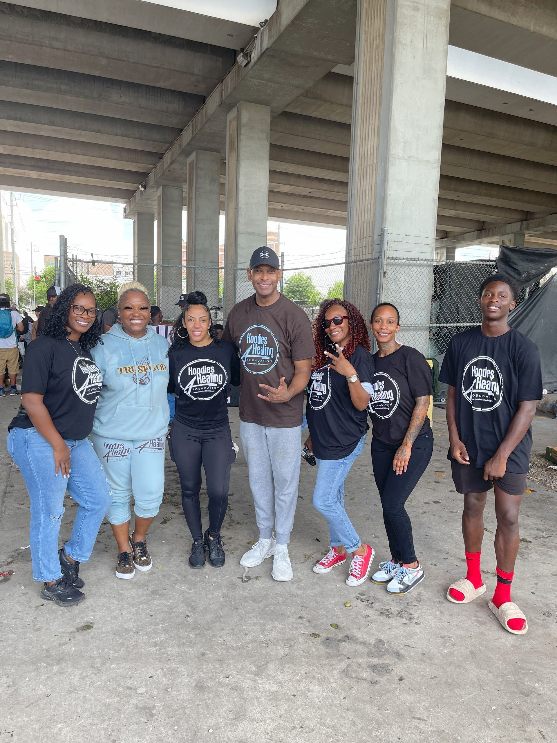 A group of people are posing for a picture under a bridge.