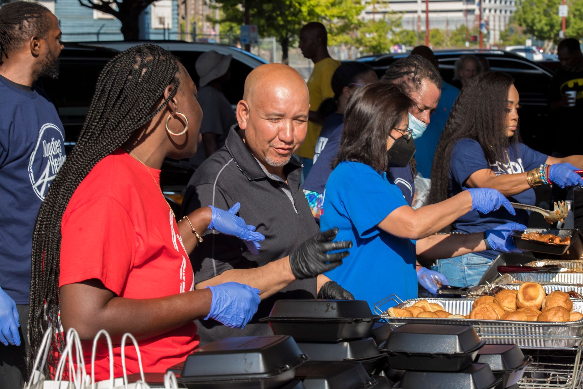 A group of people are standing around a table serving food.