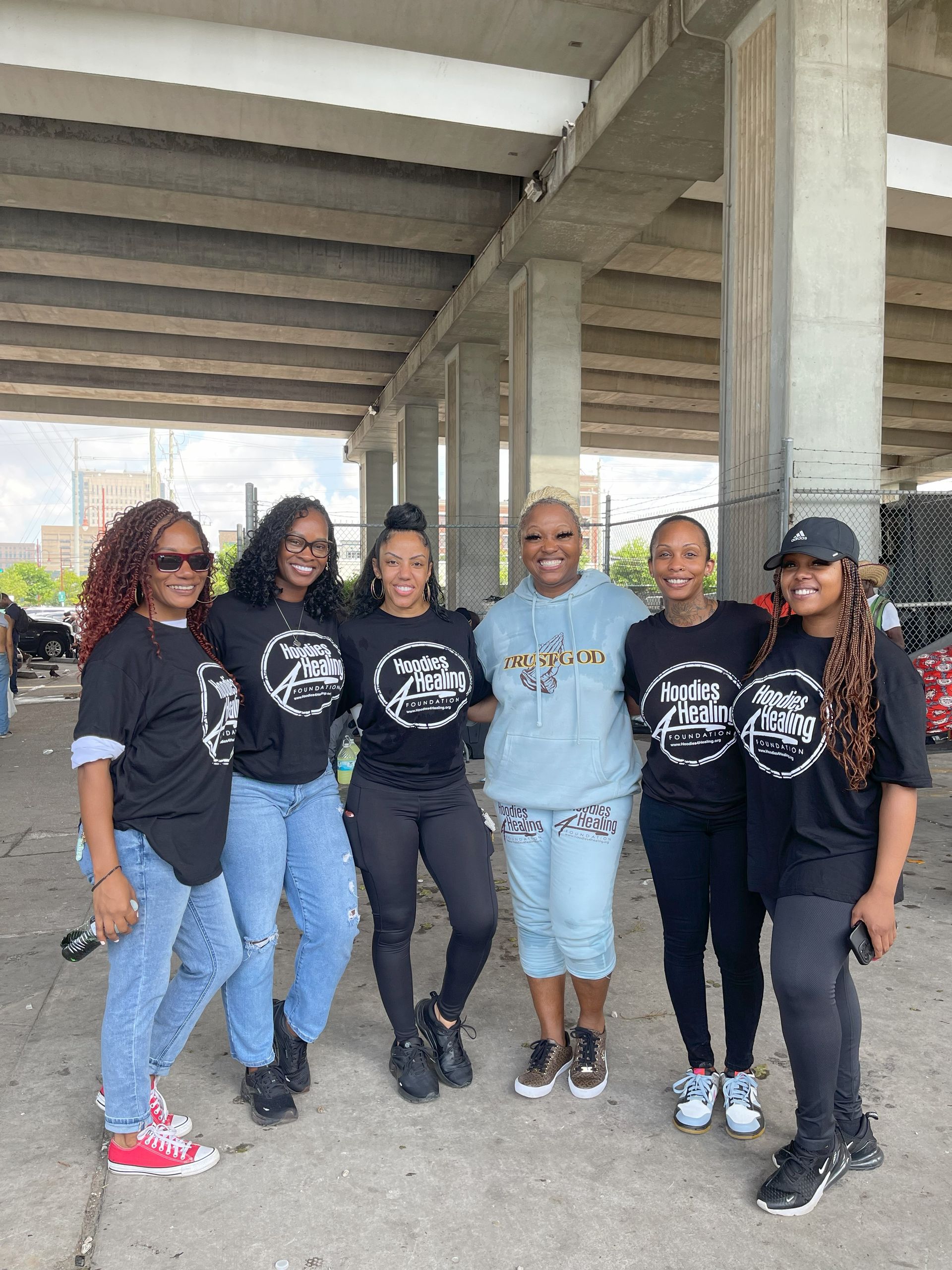 A group of women are posing for a picture under a bridge.