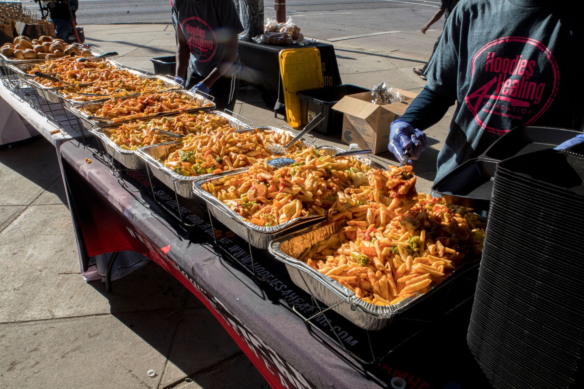 A person is standing behind a table filled with trays of food.
