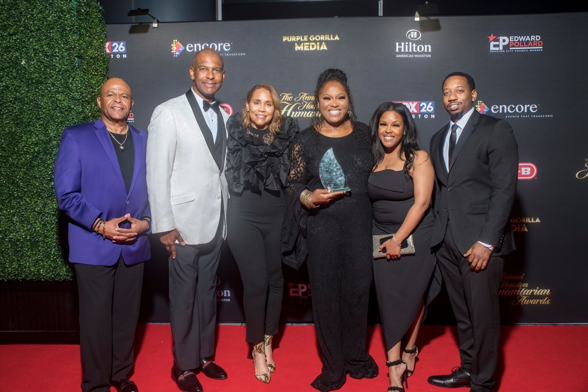 A group of people are posing for a picture on a red carpet.