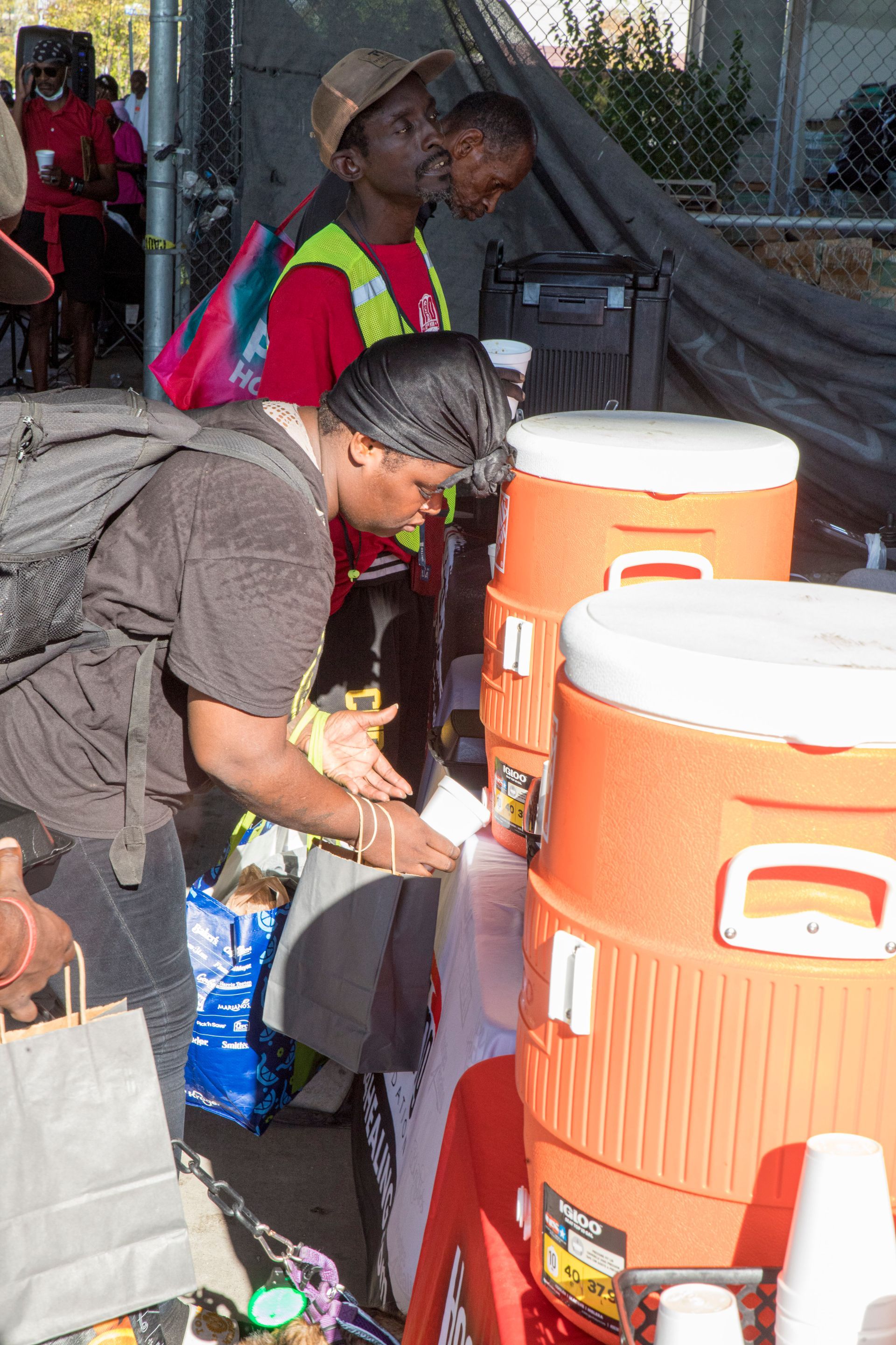 A man is standing in front of a row of orange coolers.