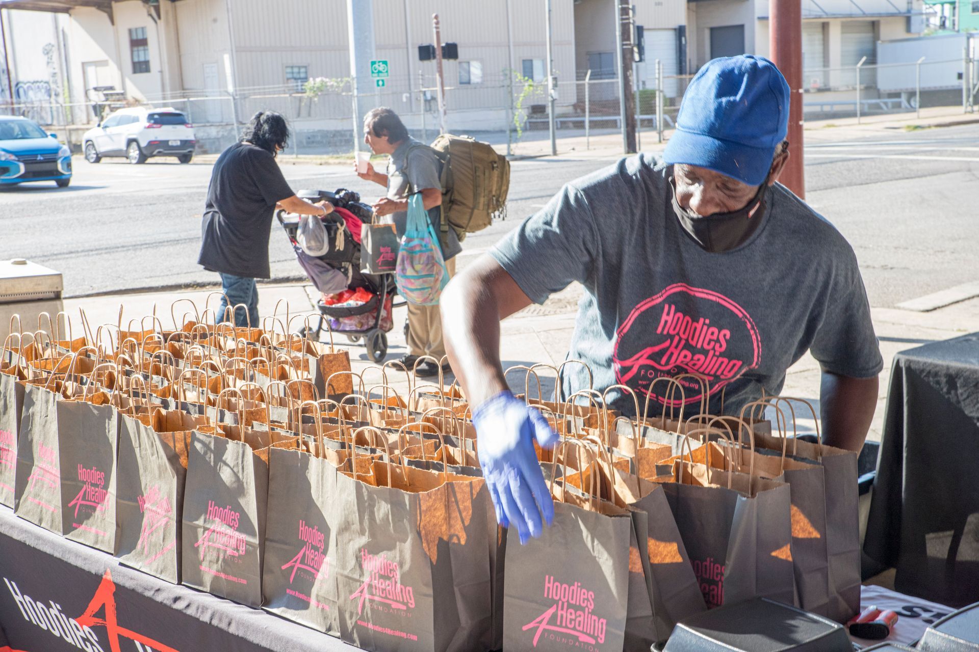 A man is standing in front of a table filled with bags of food.