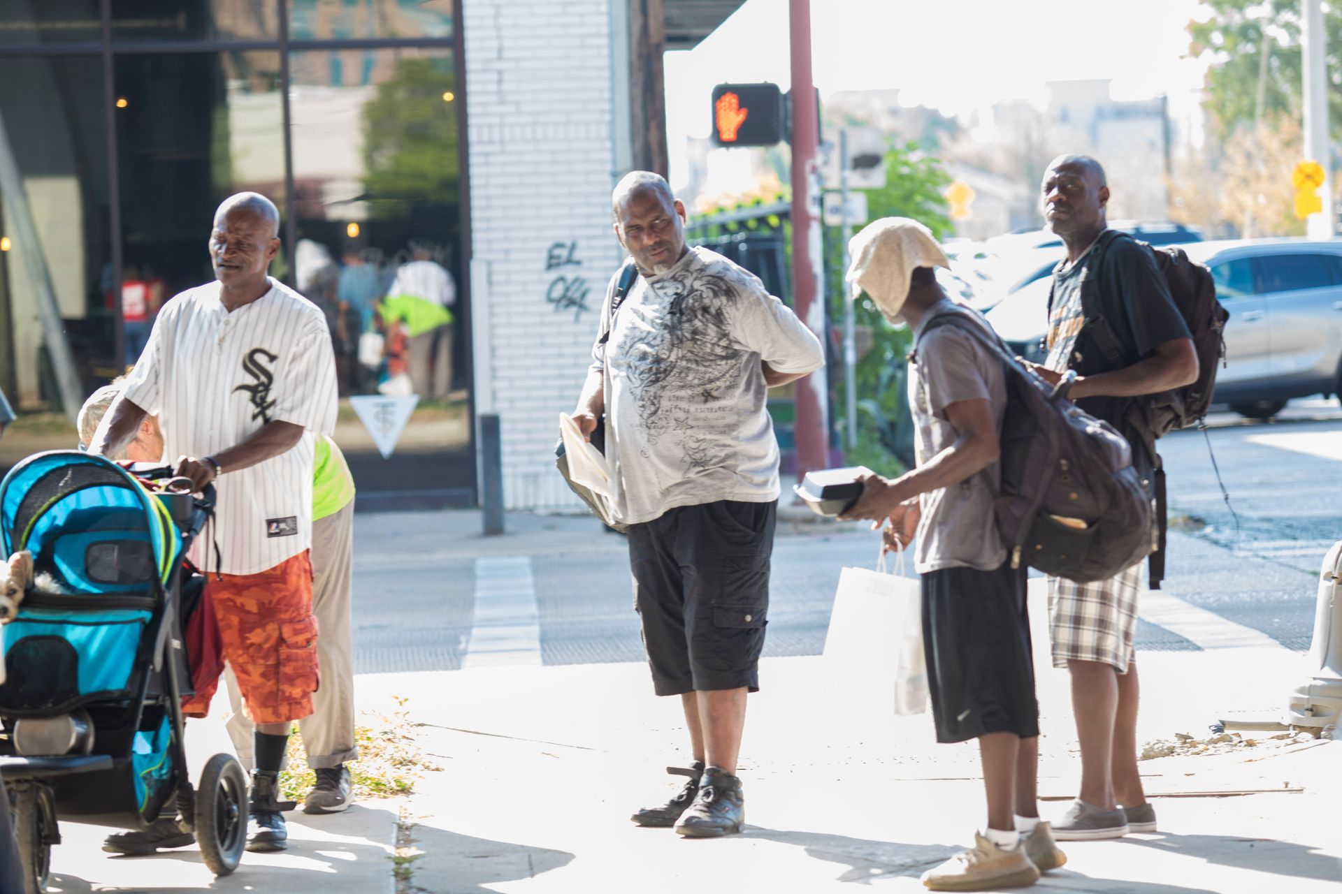 A group of men are standing on a sidewalk.