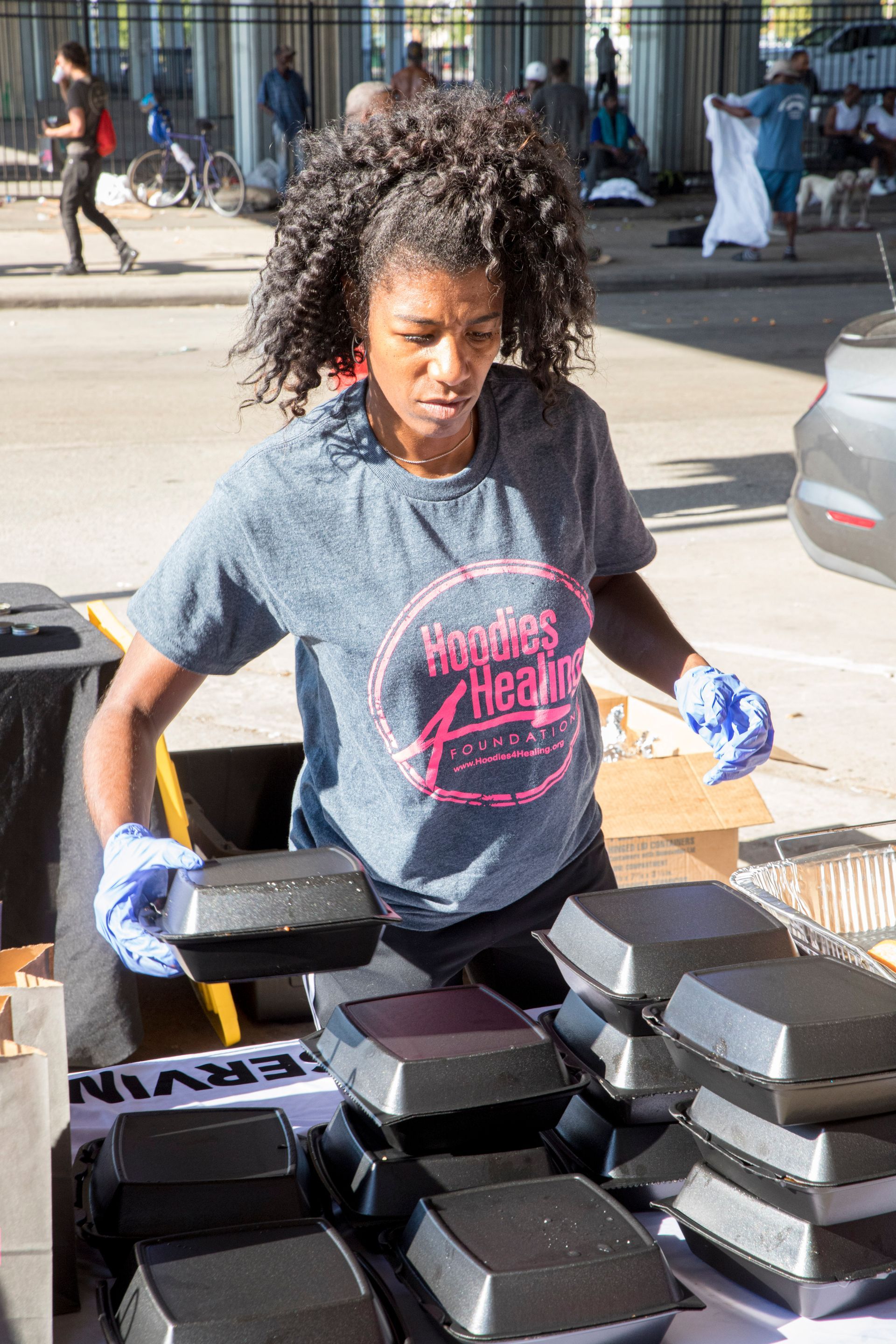 A woman is standing in front of a table filled with boxes of food.