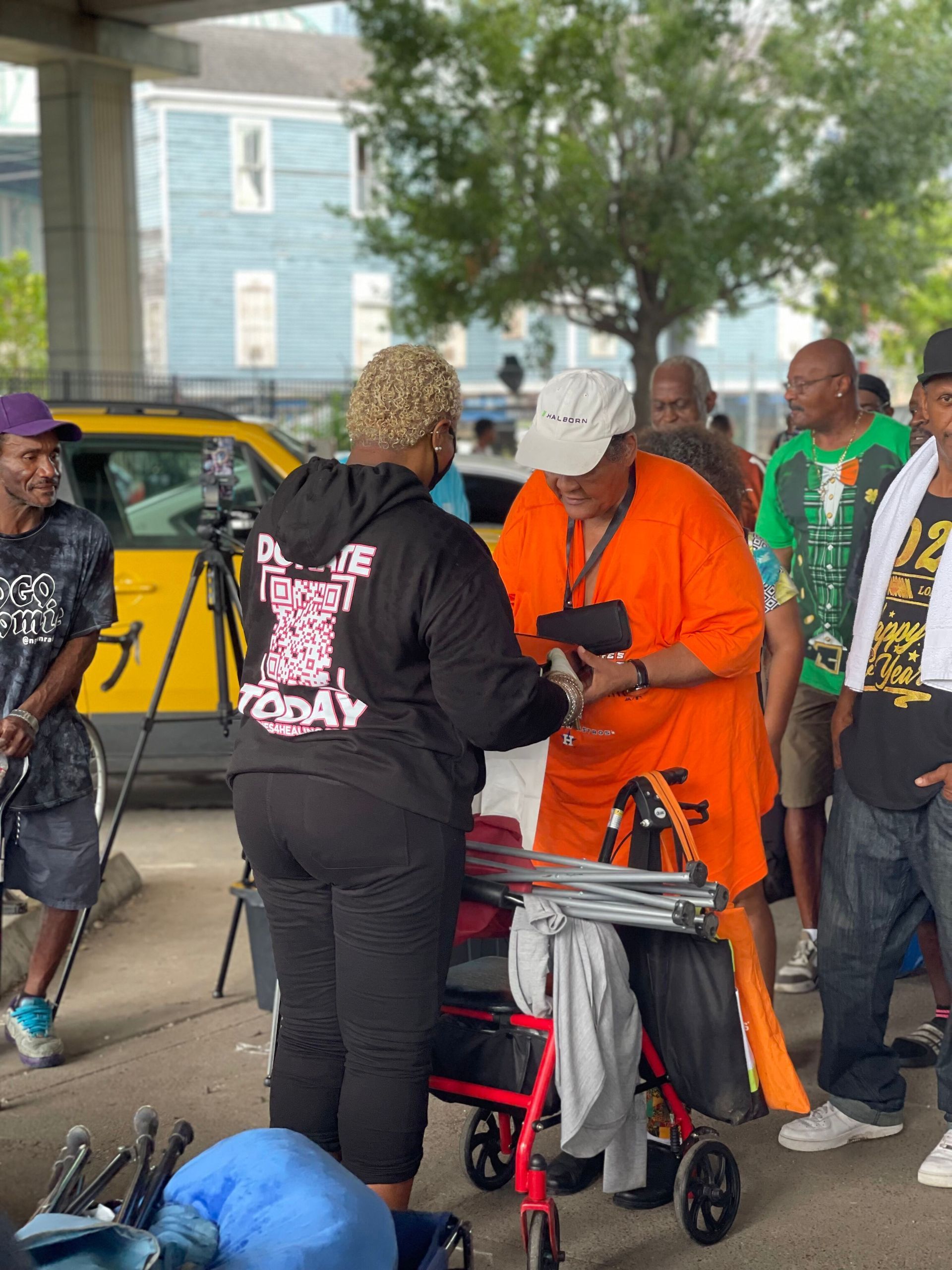 A group of people are standing around a woman with a walker