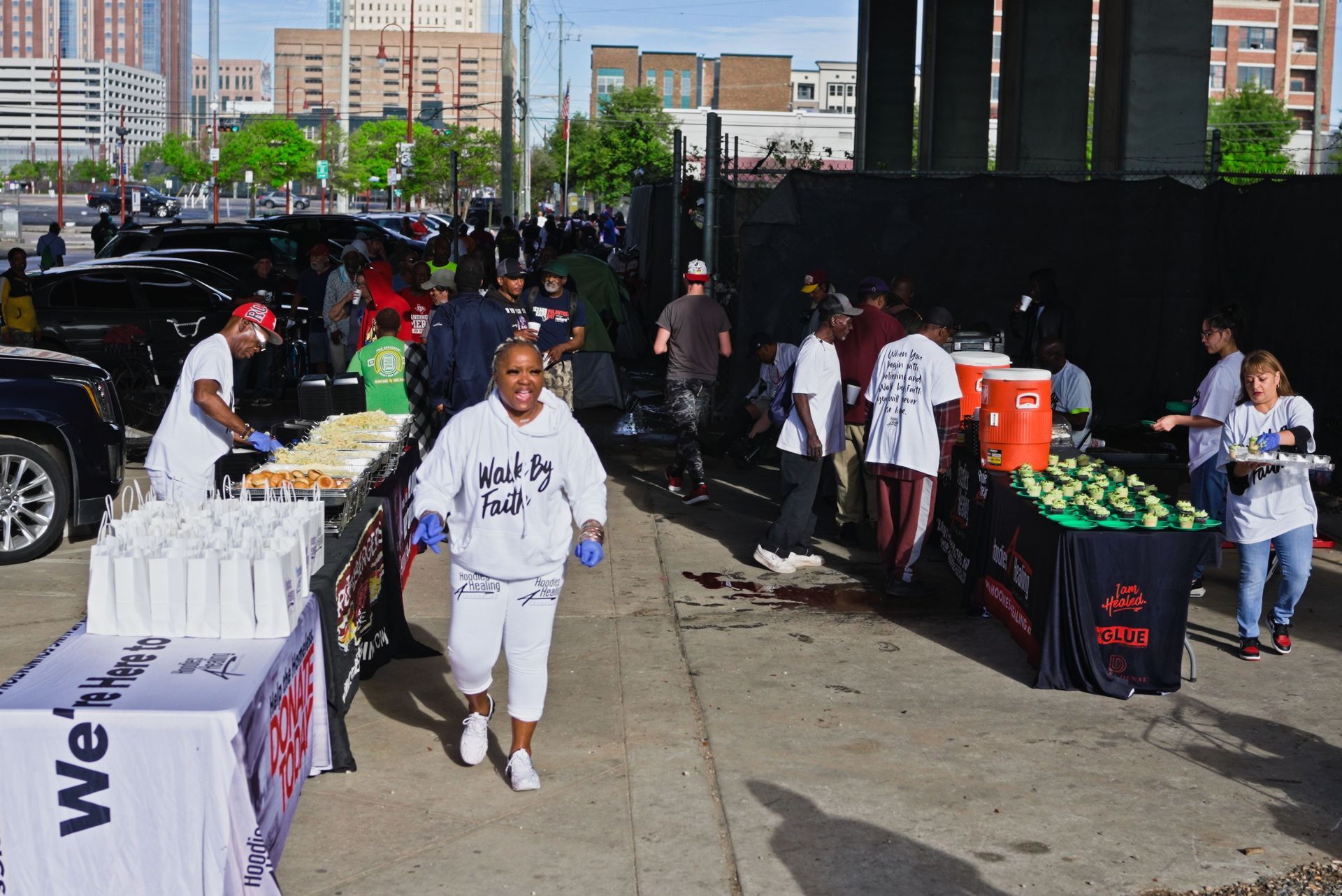 A woman in a white shirt is walking down a sidewalk in front of a table with the word we on it