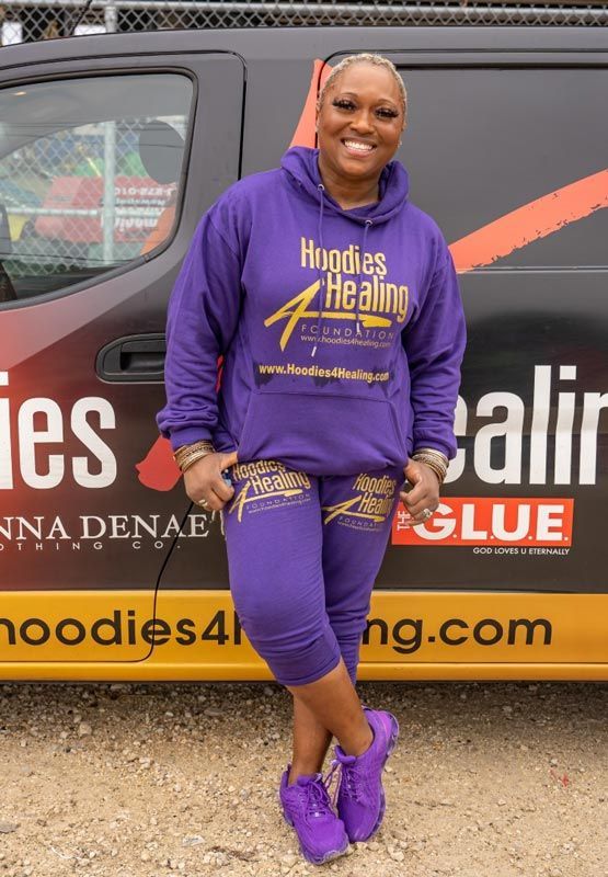 A woman in a purple hoodie is standing in front of a van.