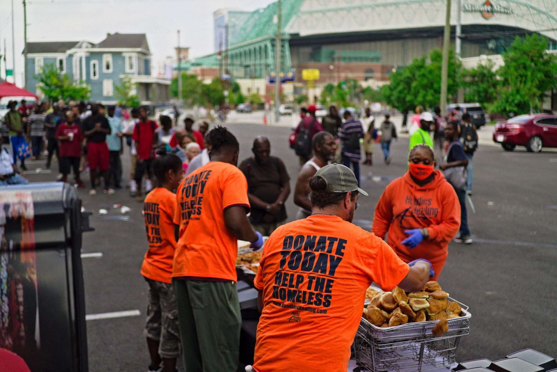 A group of people wearing orange shirts are standing in a parking lot.