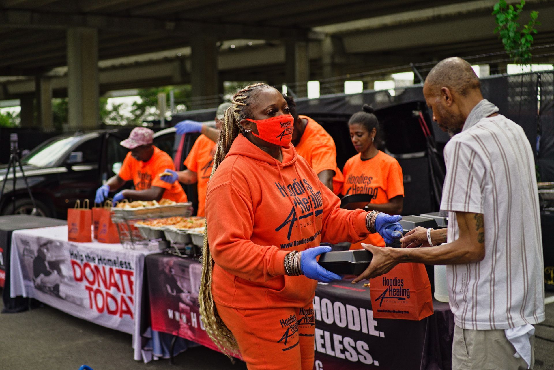A woman wearing a red mask is giving food to a man.