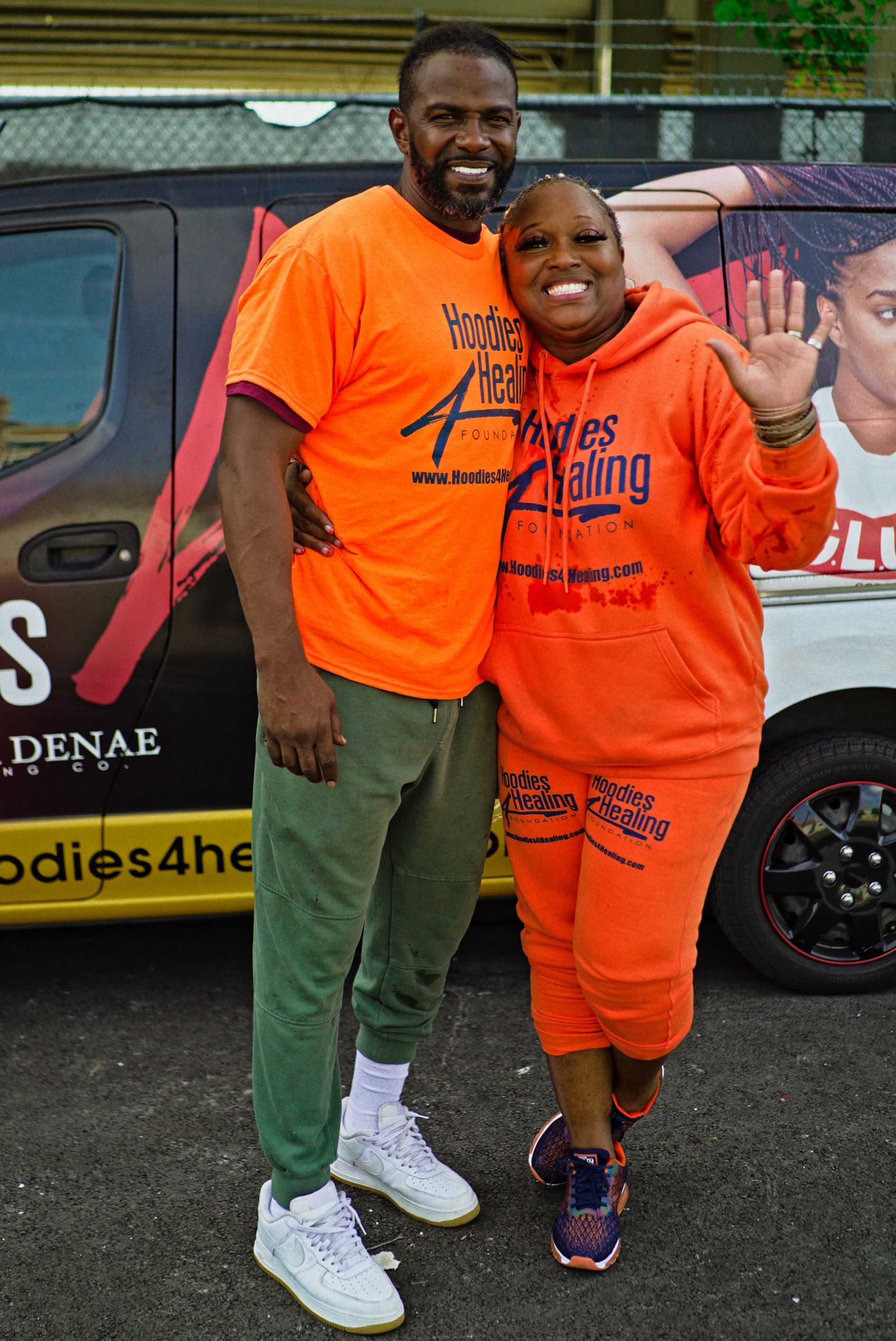 A man and a woman are standing next to each other in front of a van.