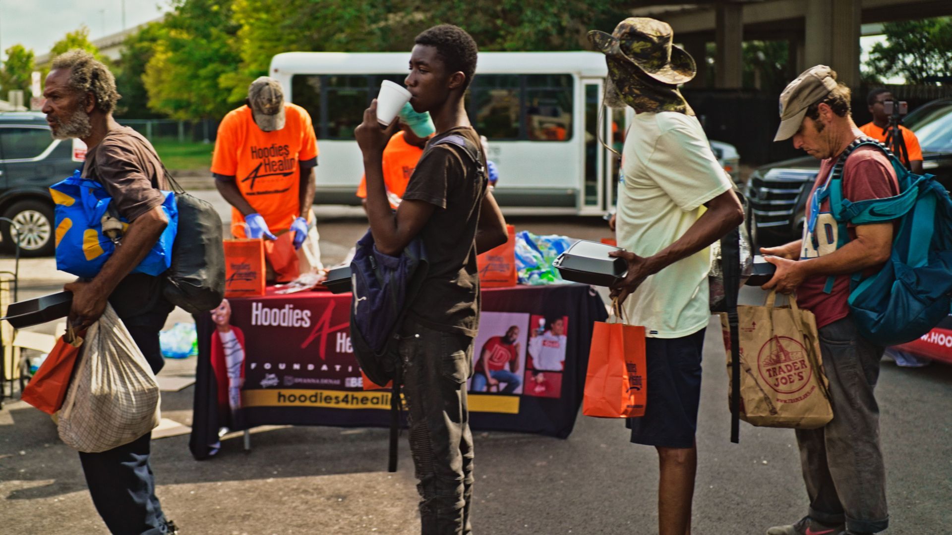 A group of people are standing around a table in a parking lot.