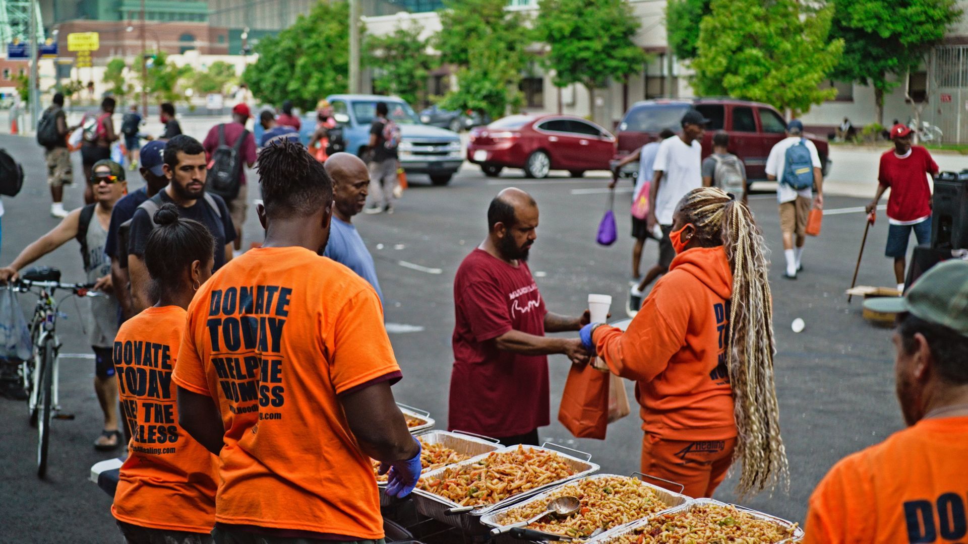 A group of people are standing around a table of food.