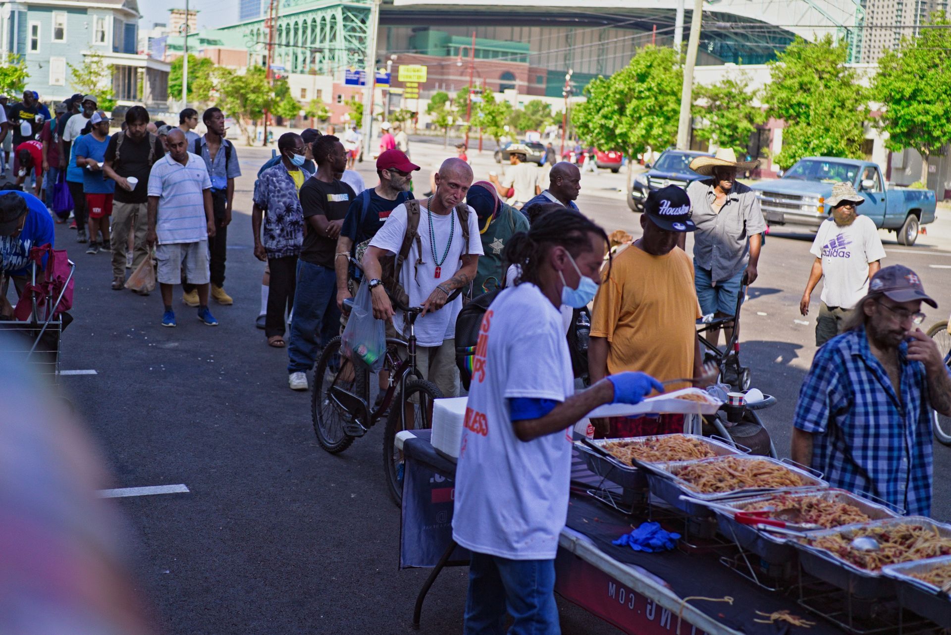 A group of people are standing in line to get food on the street.