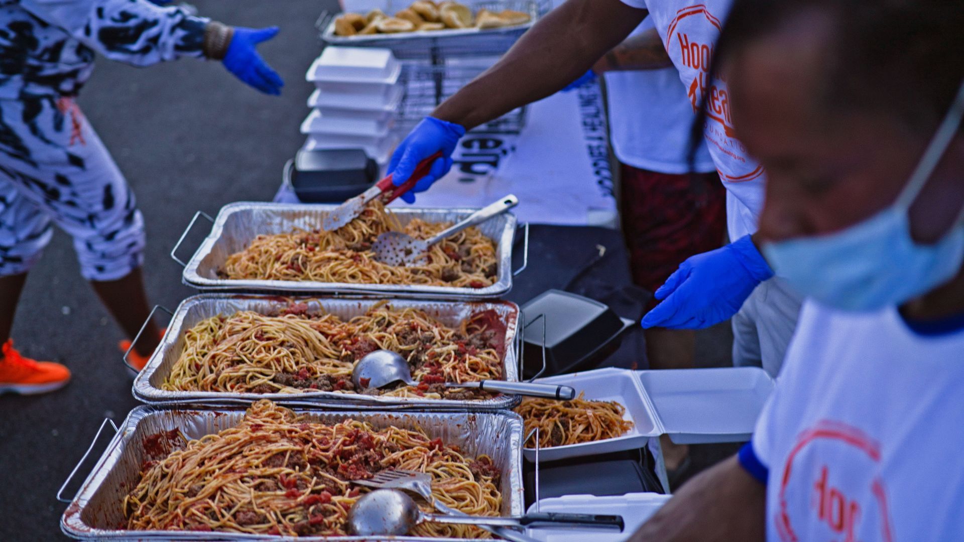 A group of people are standing around a table serving food.