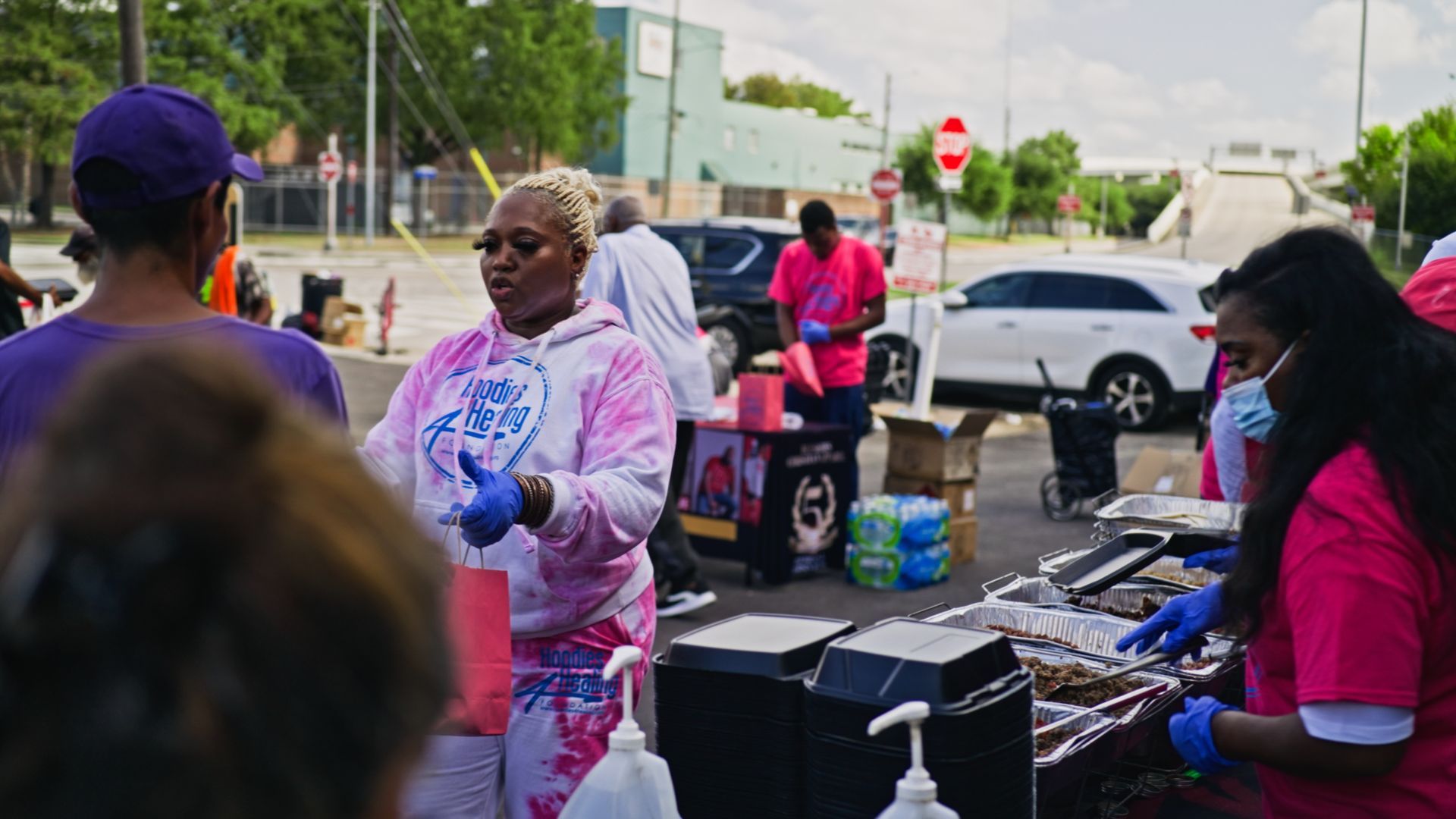 A group of people are standing around a table in a parking lot.