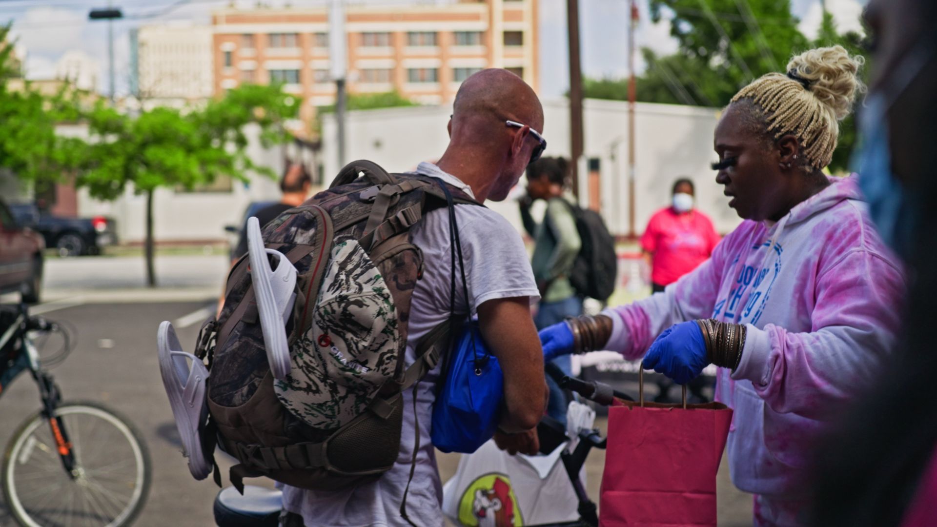 A man with a backpack is standing next to a woman wearing gloves.