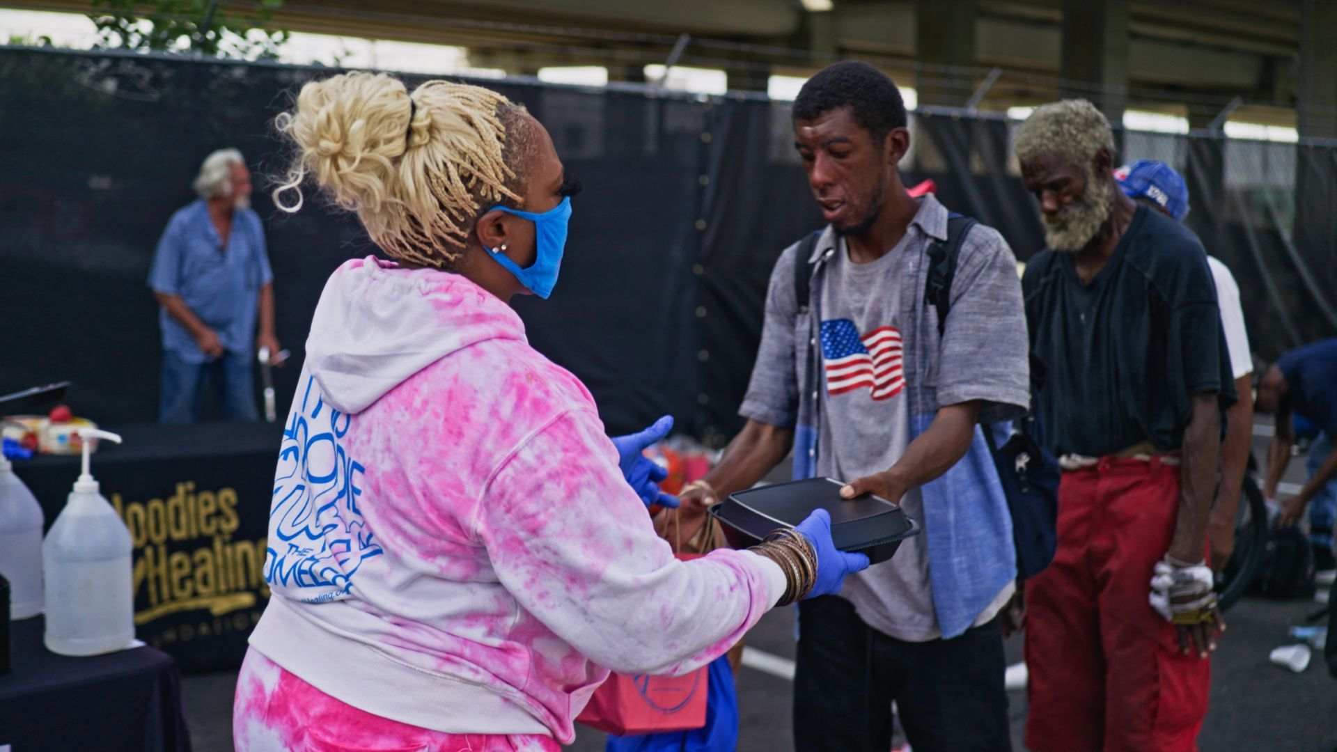 A woman wearing a mask is shaking hands with a man.