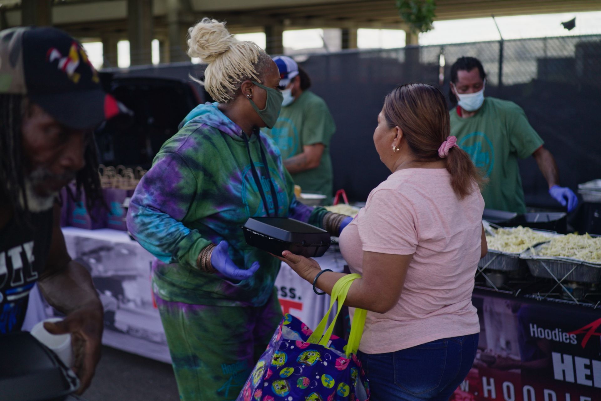 A woman in a tie dye hoodie is talking to a woman in a pink shirt.