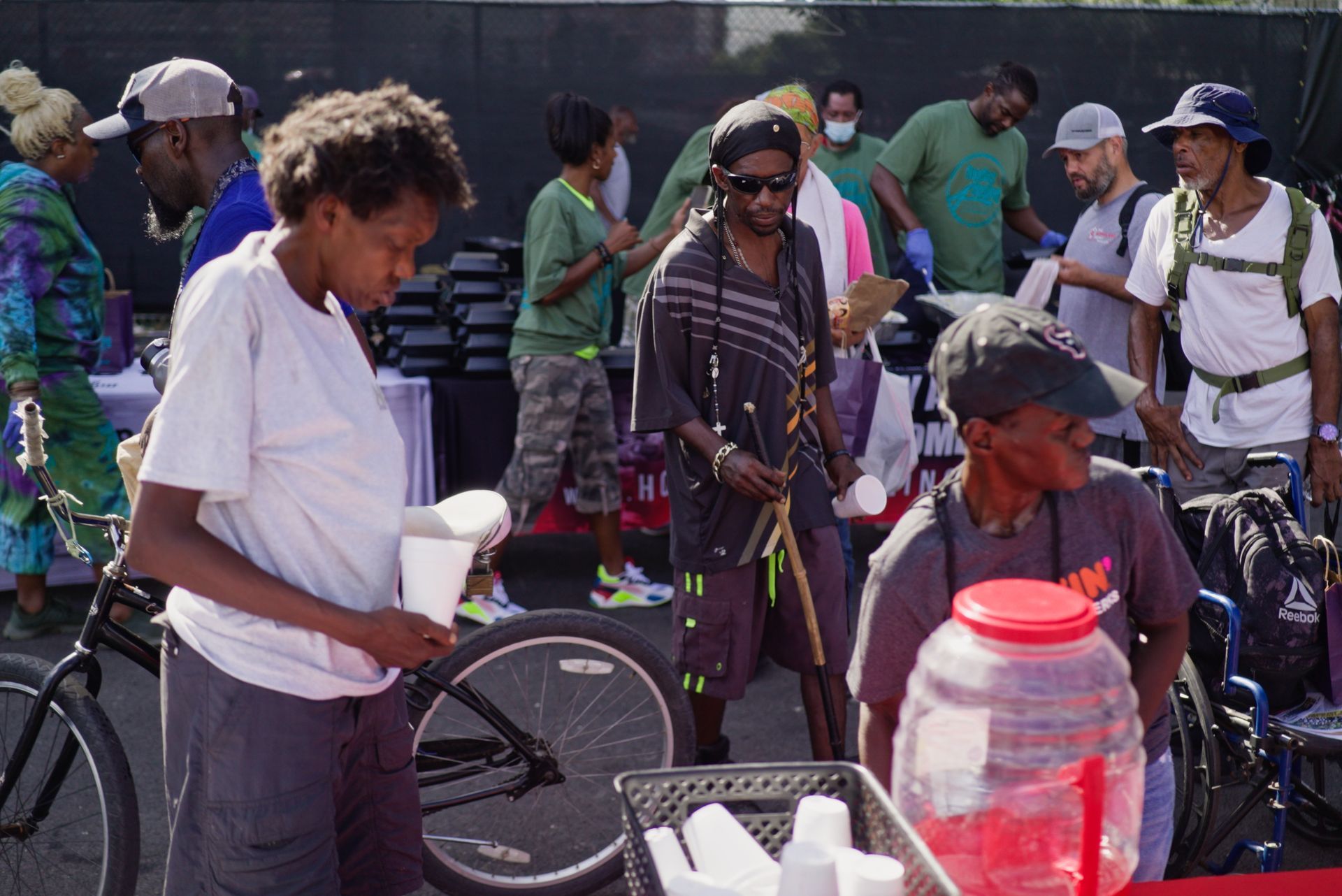 A group of people are standing around a table with a bicycle in the background.