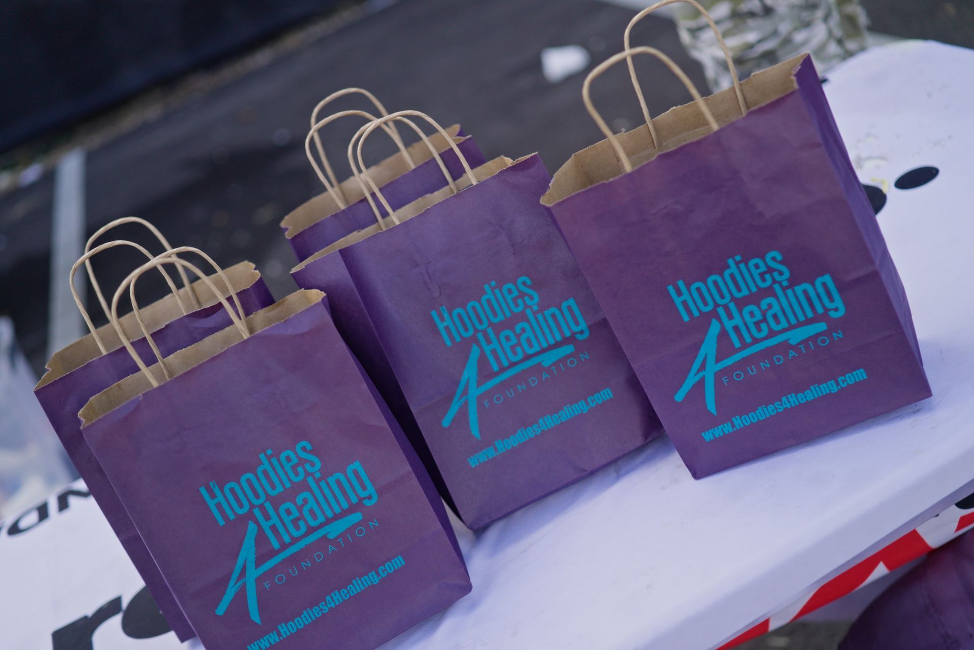 Three purple bags that say hoodies healing are sitting on a table.