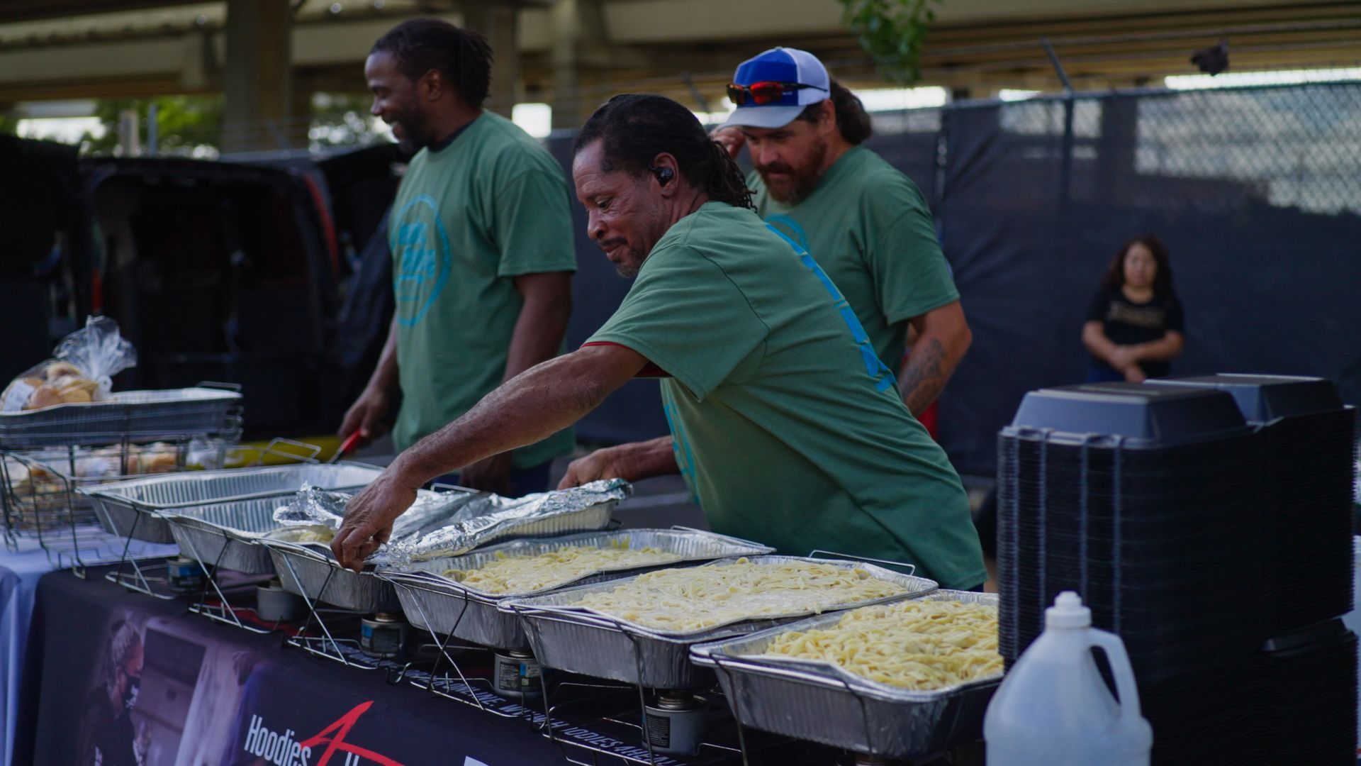 A group of men are standing around a table serving food.