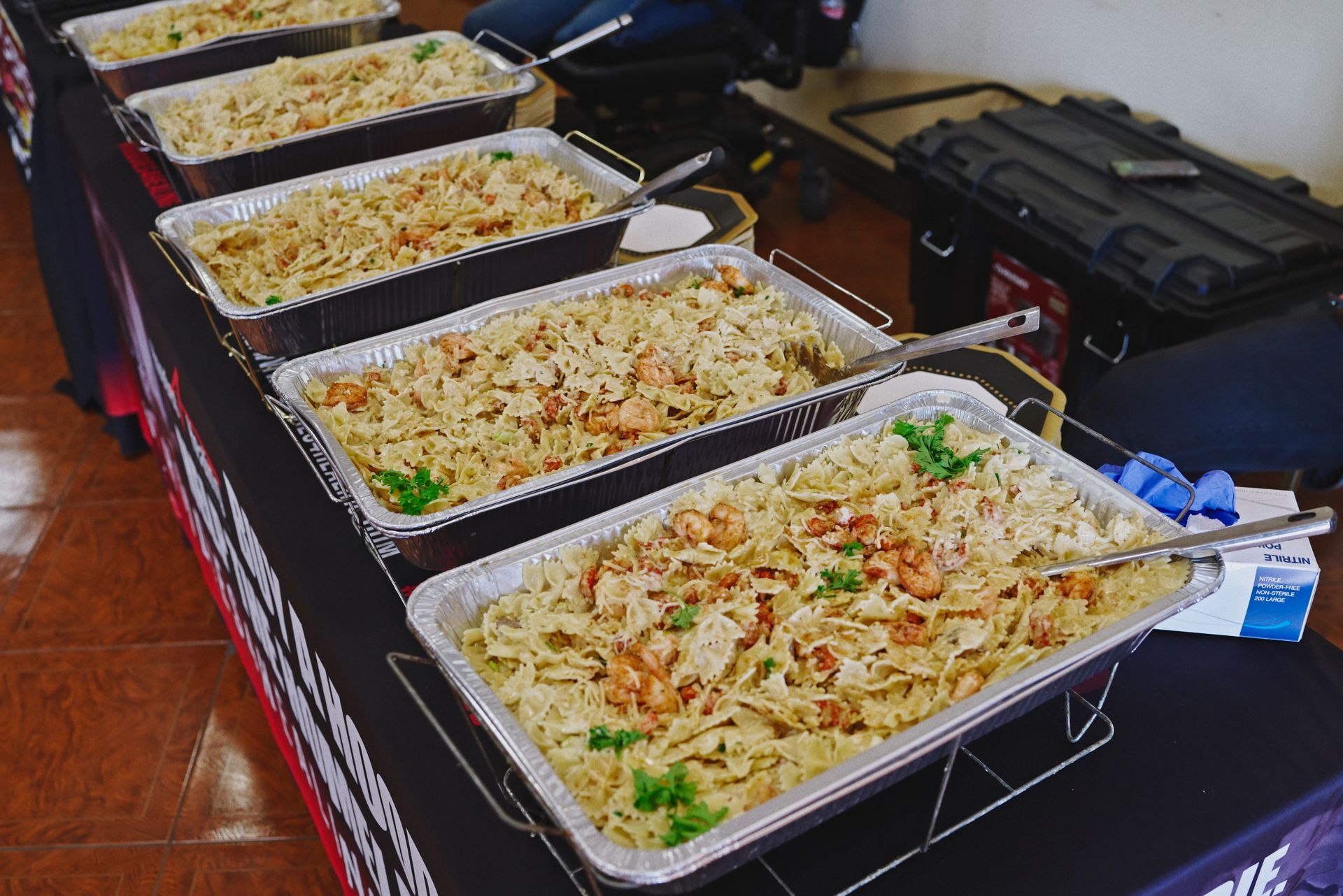 A table topped with trays of pasta and shrimp.