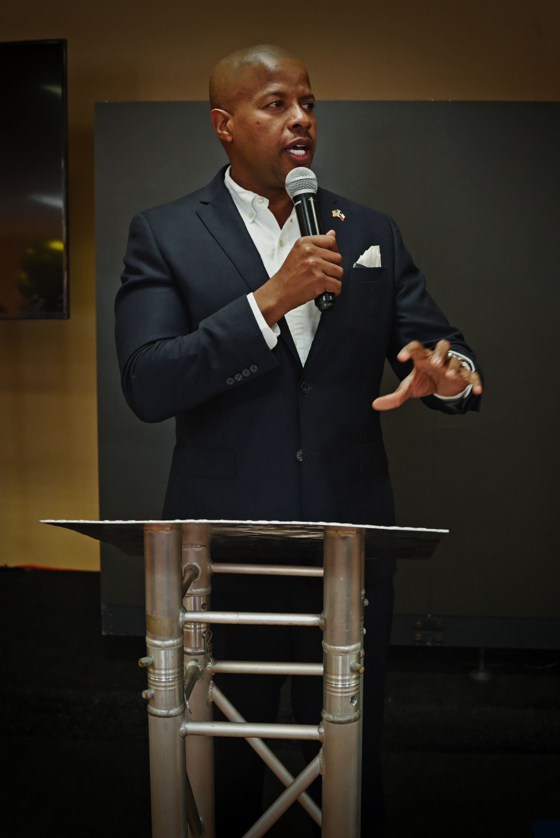 A man in a suit is standing at a podium holding a microphone
