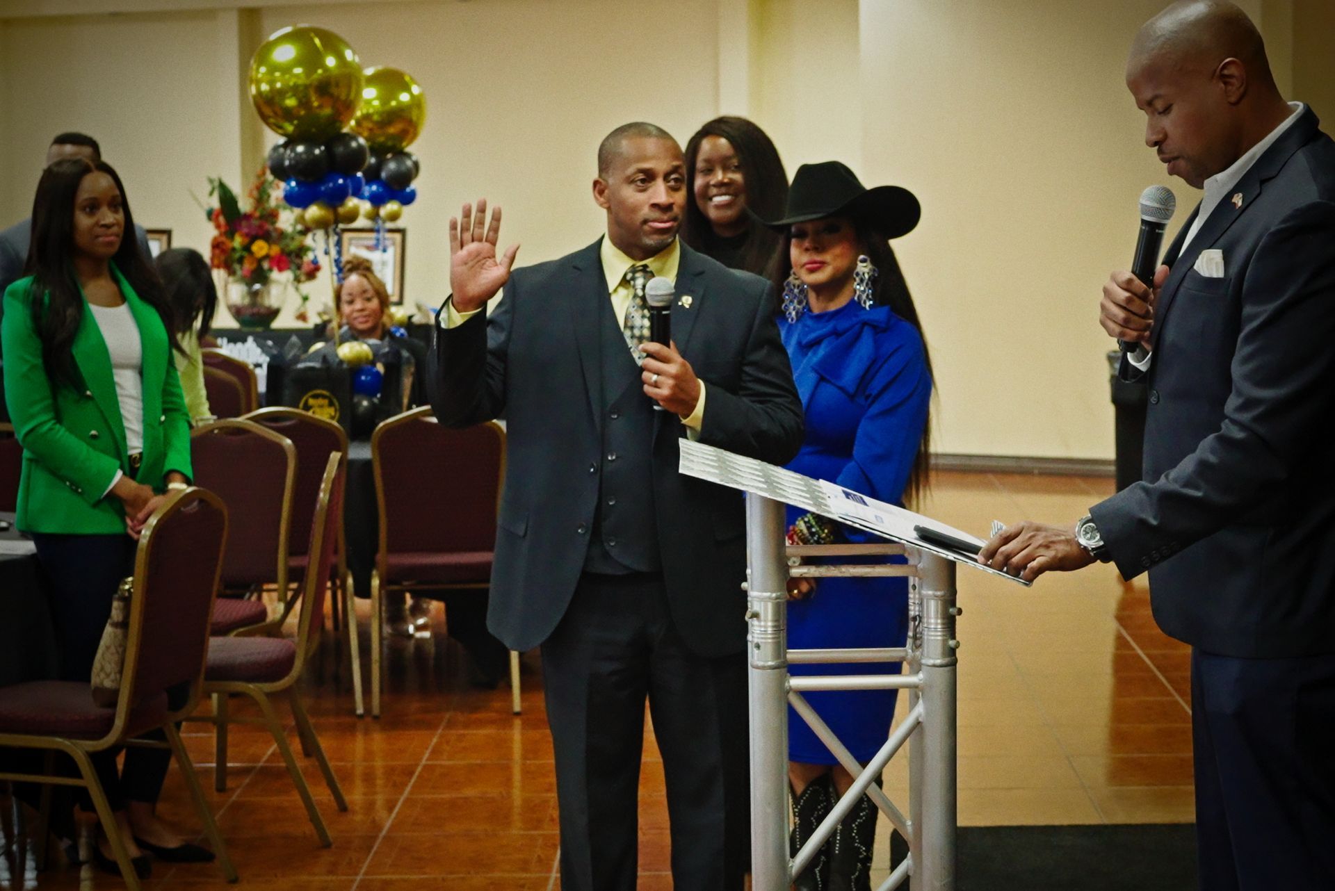 A man in a suit is standing at a podium holding a microphone.