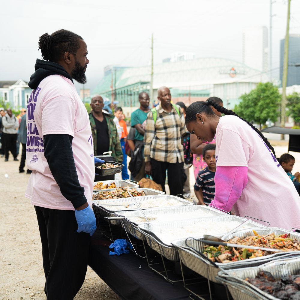 A man in a pink shirt is standing next to a woman in a pink shirt serving food.