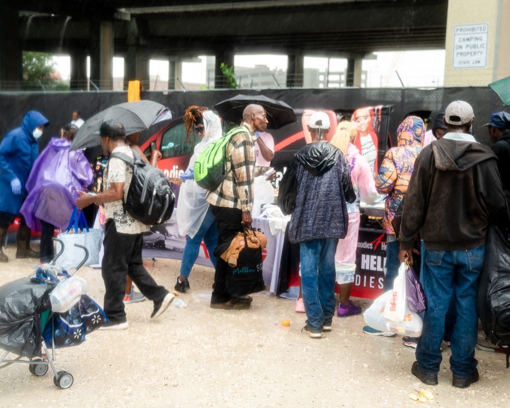 A group of people walking in front of a sign that says help dies