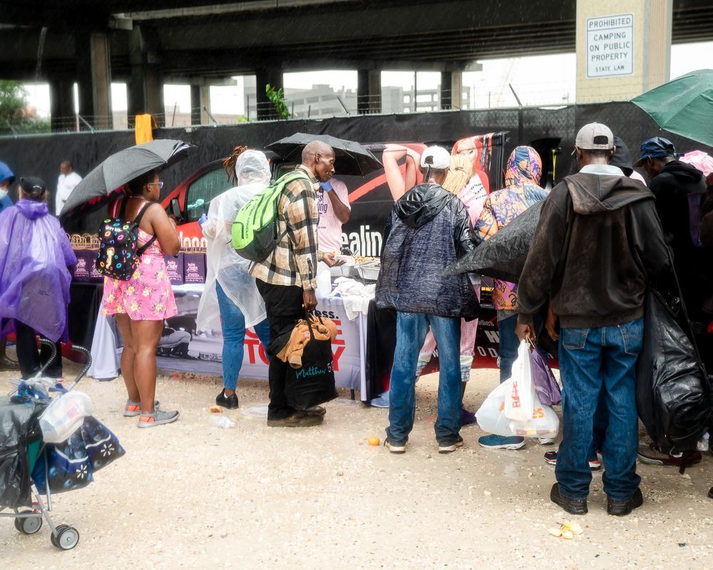 A group of people are standing around a table with umbrellas.