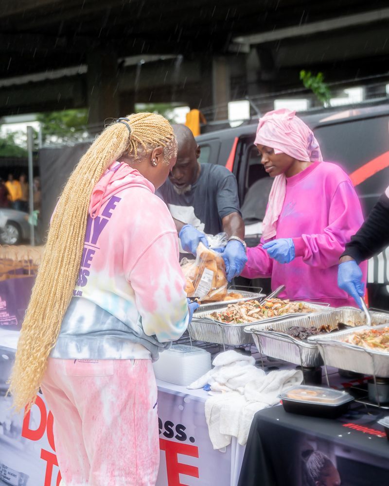 A group of people are standing around a table serving food.