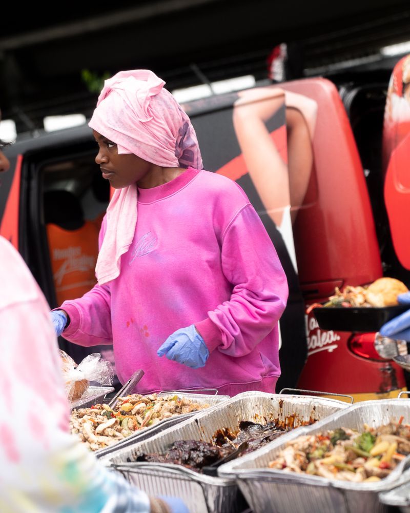 A woman in a pink sweatshirt is preparing food