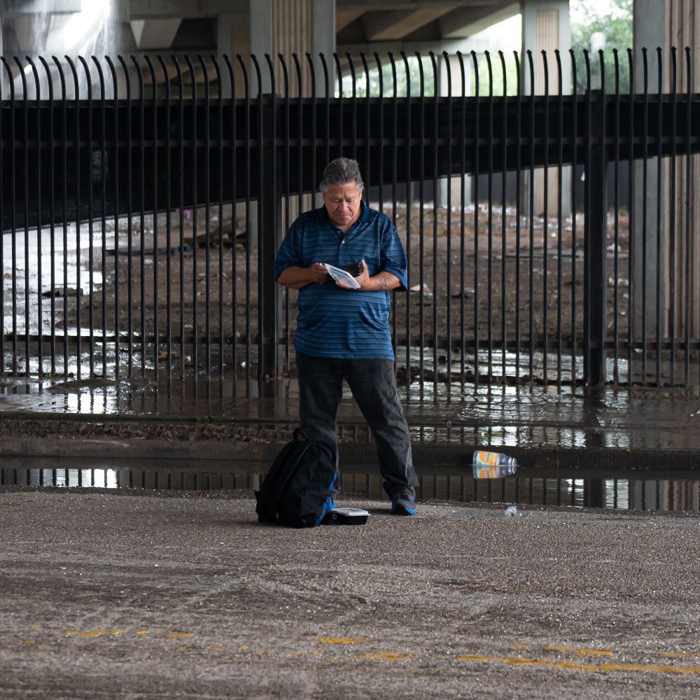 A man standing in front of a fence looking at his phone