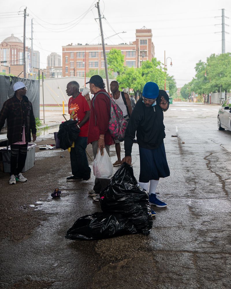 A group of people are standing on a sidewalk in the rain