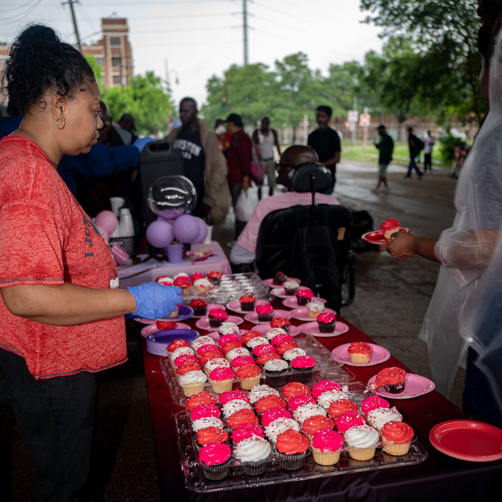 A woman is standing in front of a table full of cupcakes