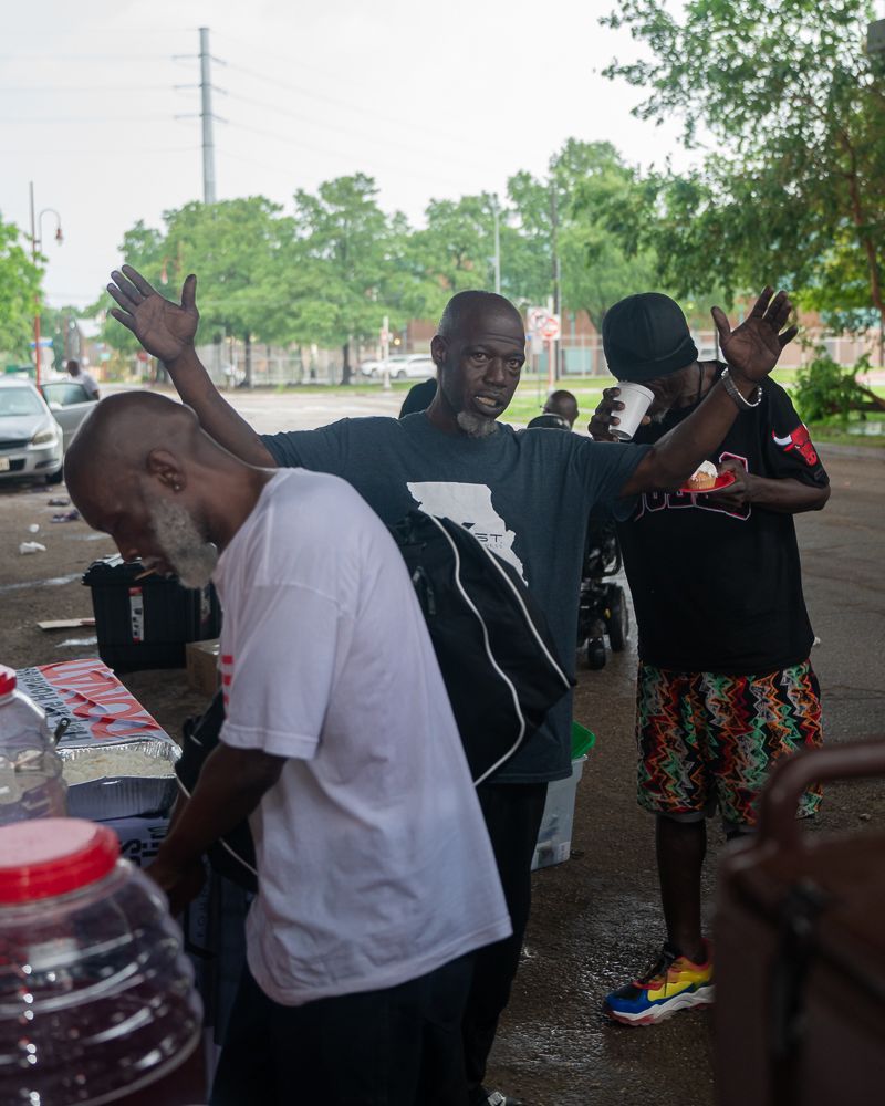 A group of men are standing in a parking lot with their arms outstretched.