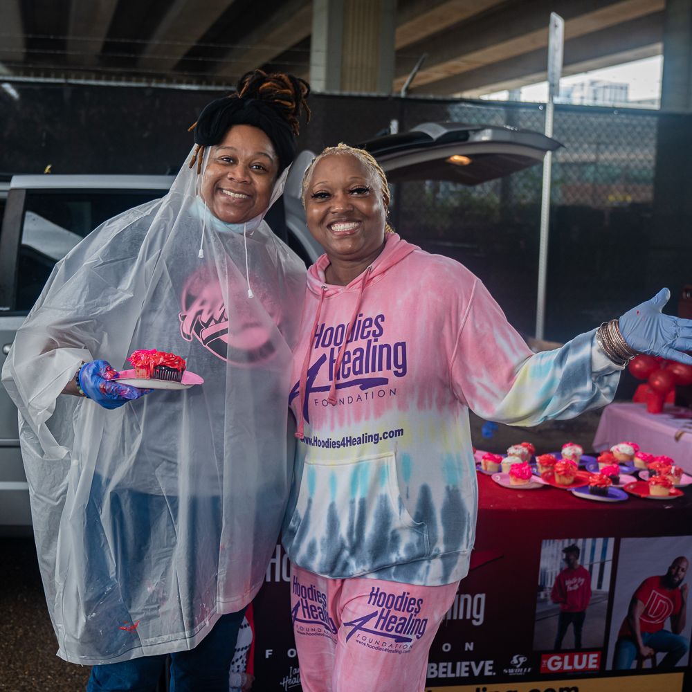 Two women are standing next to each other in front of a table.