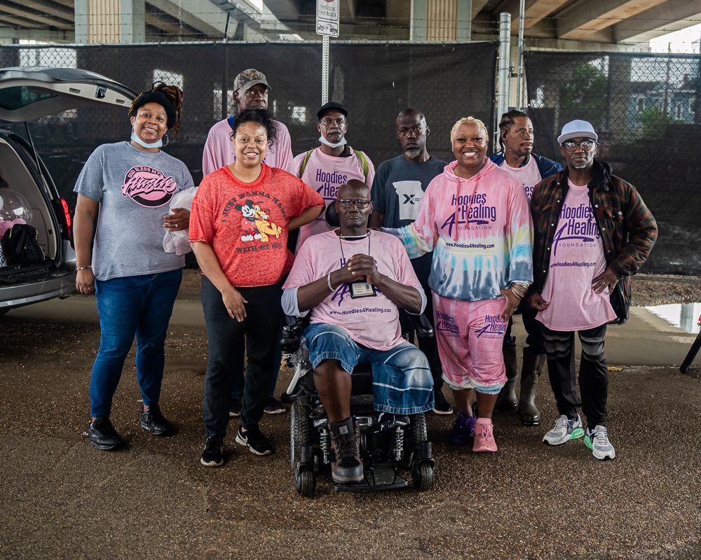 A group of people are posing for a picture with a man in a wheelchair.