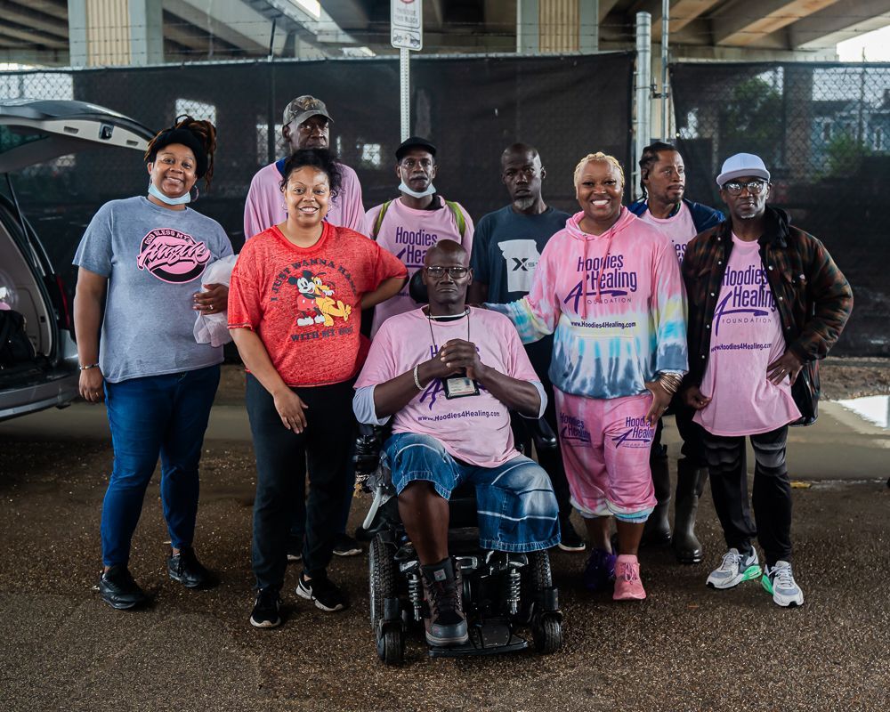 A group of people are posing for a picture with one man in a wheelchair.